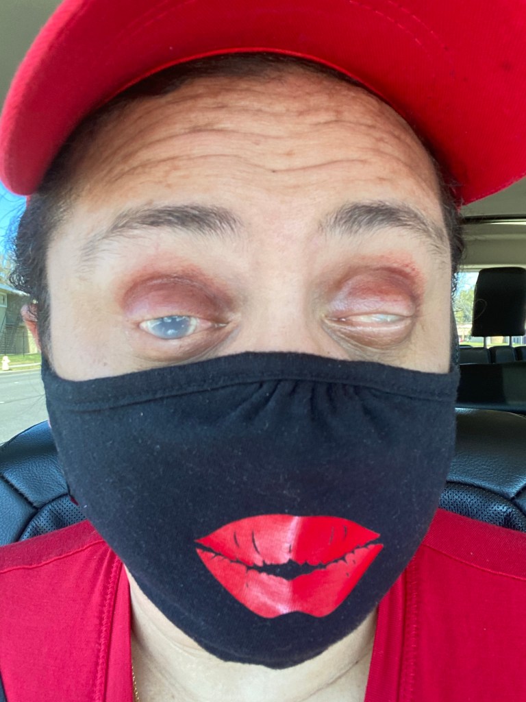 Selfie of LM wearing a red hat and a black mask with a red painted kiss mark. She's wearing reddish eye shado.